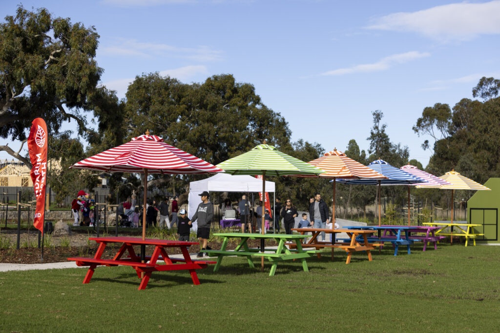 Colourful picnic tables with striped umbrellas in park
