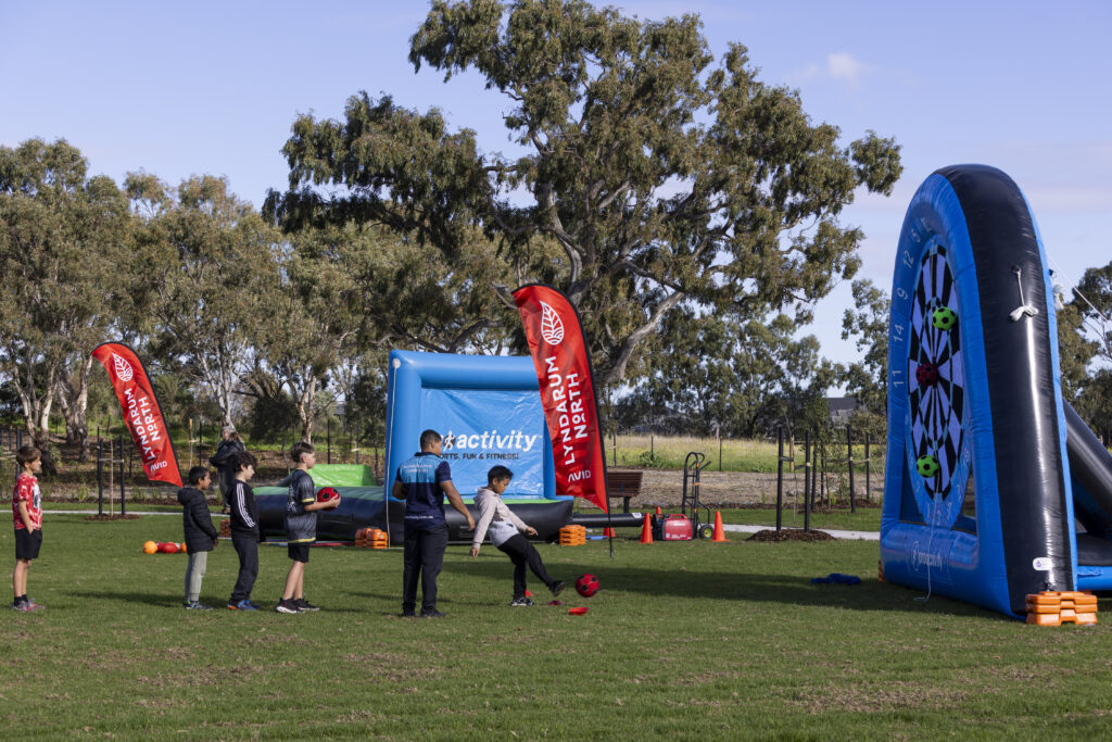 Kids kicking soccer balls at inflatable dartboard game