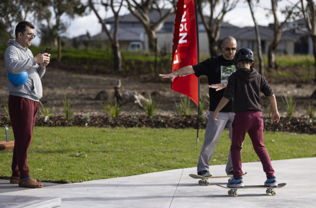 Man teaching child to skateboard at park
