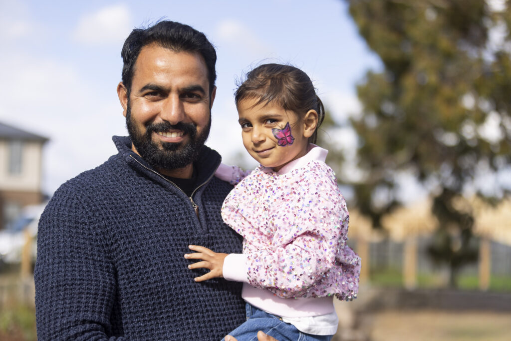 Father holding daughter with butterfly face paint