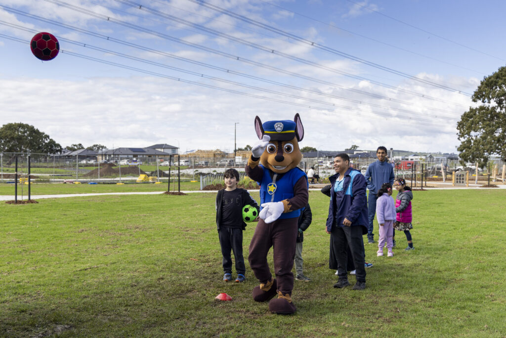 Police dog mascot playing soccer with children